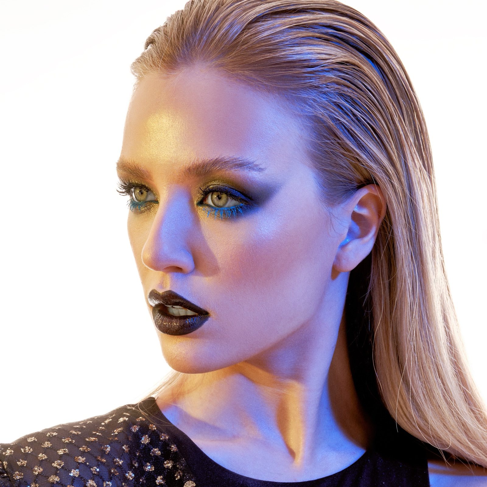 Bold avant garde makeup with a dark lip under coloured studio lighting